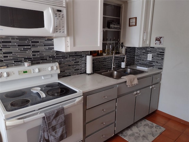 kitchen with tasteful backsplash, gray cabinetry, white appliances, sink, and white cabinets