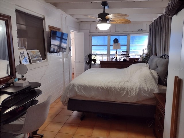 tiled bedroom featuring beam ceiling, ceiling fan, and wooden walls