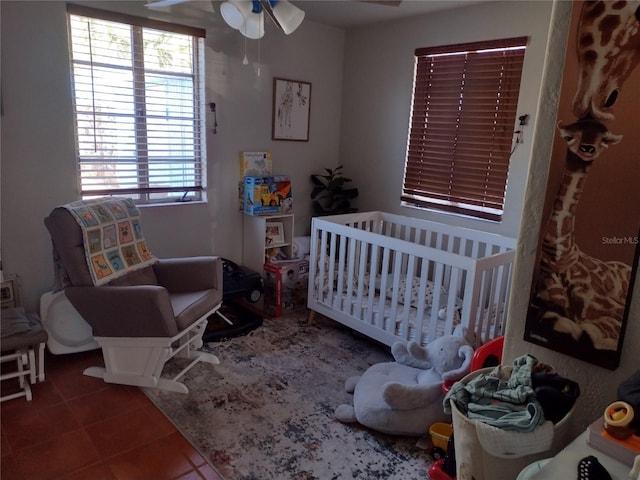 tiled bedroom with ceiling fan and a nursery area