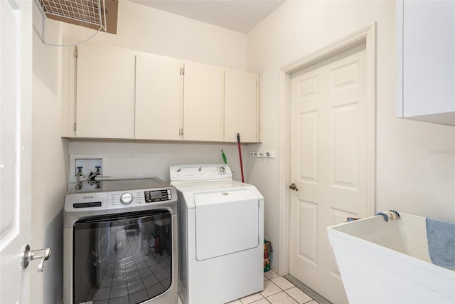 washroom with washer and clothes dryer, light tile patterned floors, and cabinets