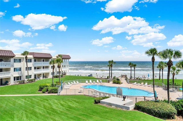 view of swimming pool featuring a patio, a water view, and a lawn