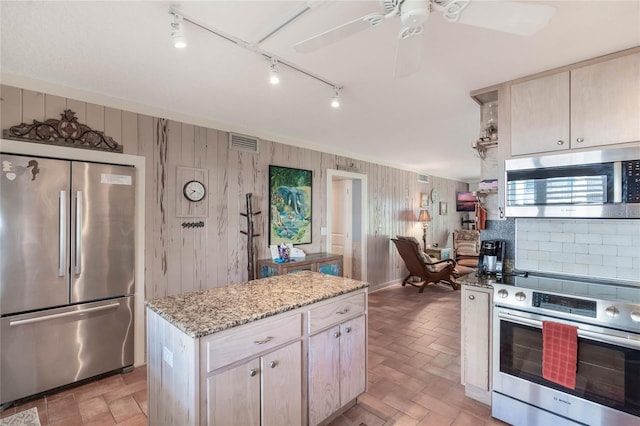 3663 S Atlantic Ave Unit 11D, New Smyrna Beach, FL 32169 - kitchen featuring a center island, wooden walls, ceiling fan, light stone countertops, and appliances with stainless steel finishes