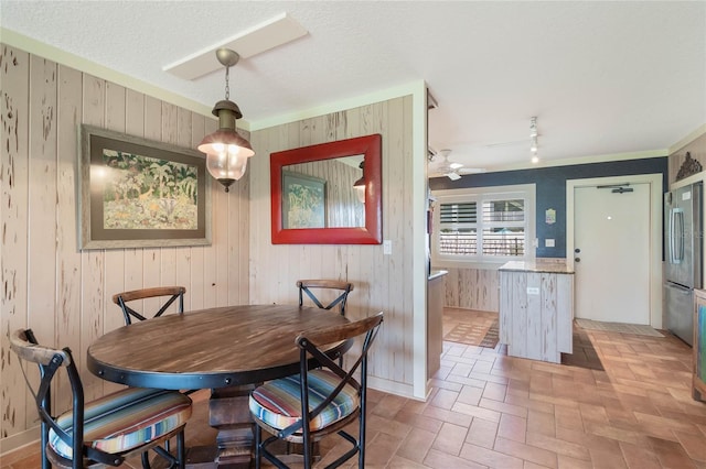 3663 S Atlantic Ave Unit 11D, New Smyrna Beach, FL 32169 - dining space featuring ceiling fan, wooden walls, rail lighting, and a textured ceiling