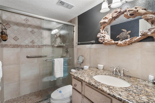 3663 S Atlantic Ave Unit 11D, New Smyrna Beach, FL 32169 - bathroom with vanity, toilet, a textured ceiling, tile walls, and an enclosed shower