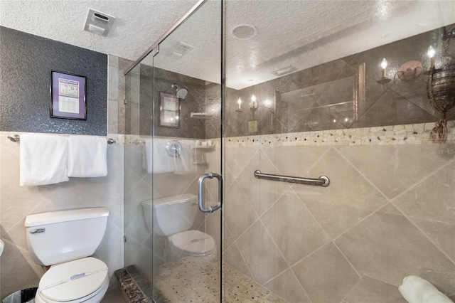 3663 S Atlantic Ave Unit 11D, New Smyrna Beach, FL 32169 - bathroom featuring tile walls, a shower with shower door, a textured ceiling, and toilet