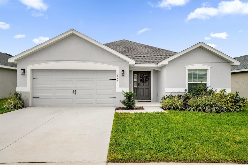 single story home with a garage and a front lawn