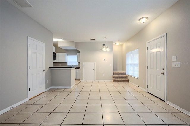 kitchen with white cabinets, light tile patterned floors, a chandelier, and hanging light fixtures