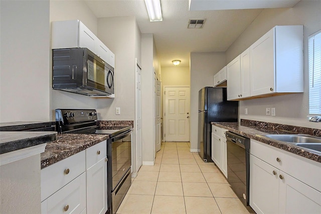 kitchen featuring sink, white cabinets, light tile patterned flooring, dark stone countertops, and black appliances