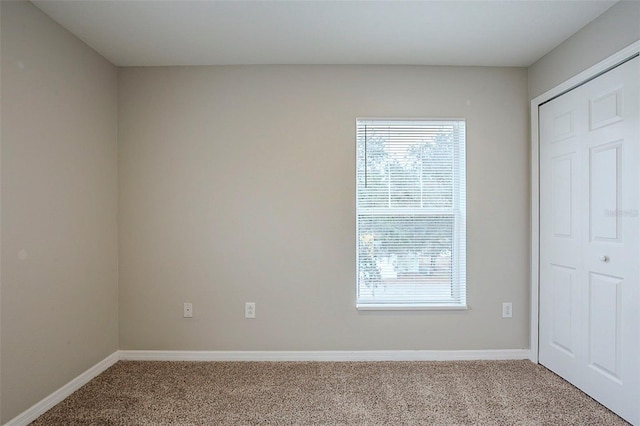 unfurnished bedroom with light colored carpet and a closet