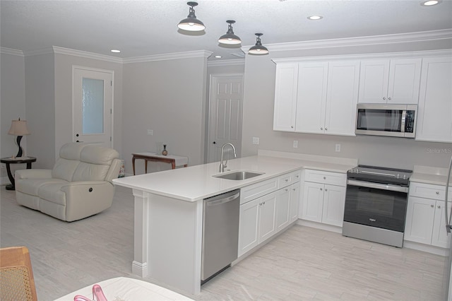 kitchen featuring pendant lighting, sink, kitchen peninsula, white cabinetry, and stainless steel appliances