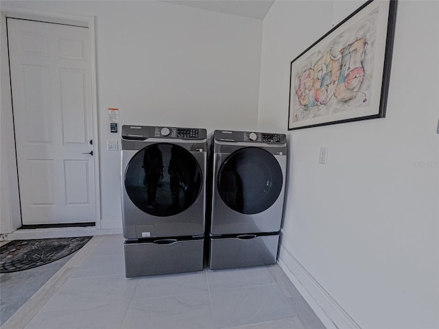 laundry area with washing machine and dryer and light tile patterned floors