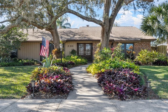 ranch-style house featuring french doors and a front lawn