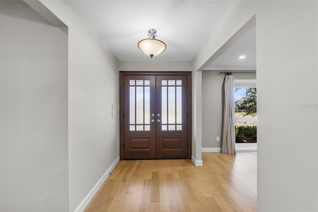 entryway with french doors, a textured ceiling, and light hardwood / wood-style flooring