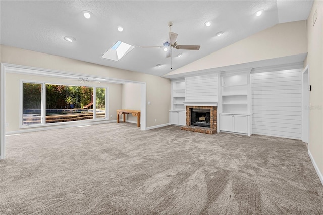 unfurnished living room featuring ceiling fan, carpet, lofted ceiling with skylight, and a brick fireplace