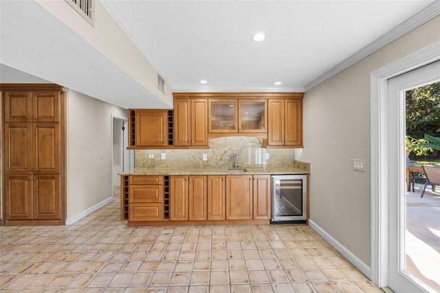 kitchen with decorative backsplash, light stone counters, beverage cooler, crown molding, and sink