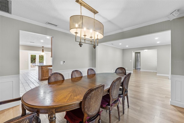 dining room with an inviting chandelier, ornamental molding, a textured ceiling, and french doors