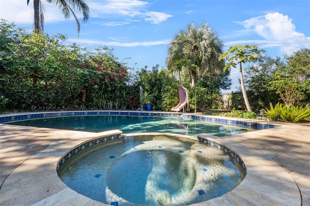 view of pool featuring an in ground hot tub, a patio area, and a water slide