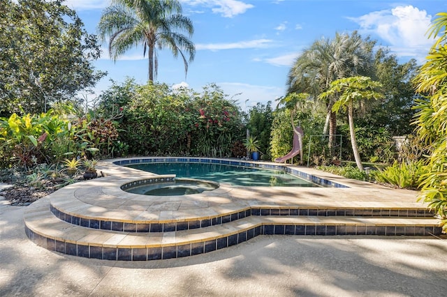 view of pool with an in ground hot tub and a water slide