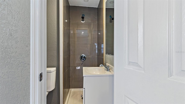 bathroom featuring tiled shower, vanity, and toilet