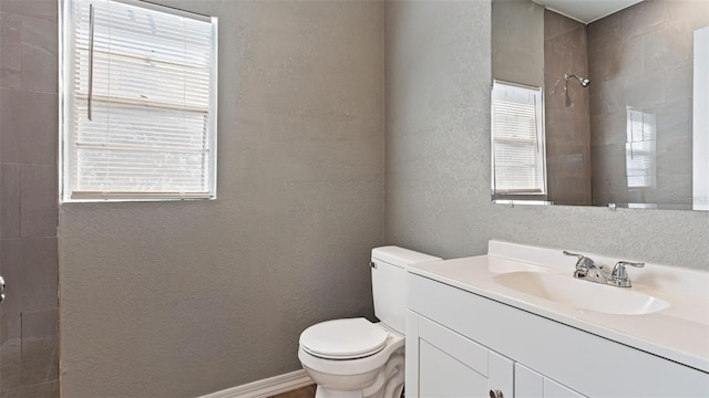 bathroom with vanity, toilet, and a tile shower