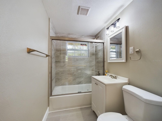 full bathroom with vanity, toilet, shower / bath combination with glass door, and a textured ceiling