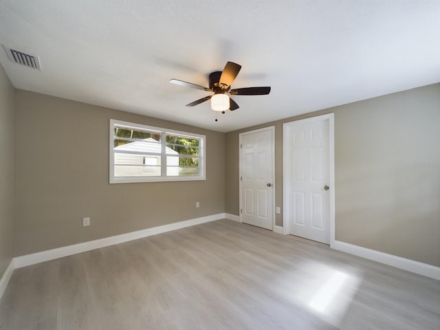 unfurnished bedroom with ceiling fan, two closets, and light wood-type flooring