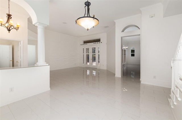 spare room with a chandelier, ornate columns, ornamental molding, and french doors