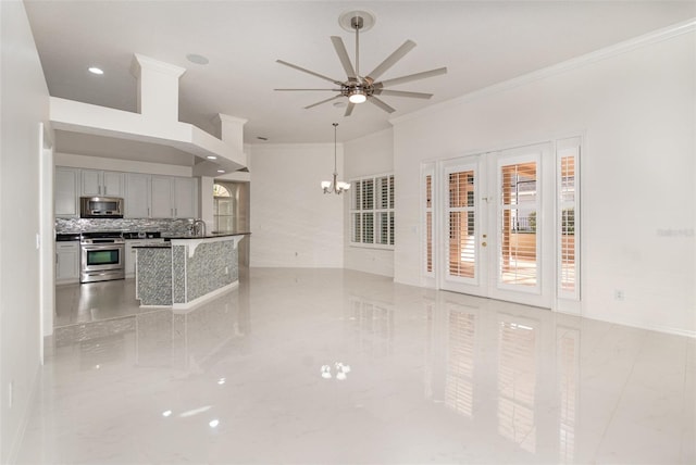 unfurnished living room with ceiling fan with notable chandelier, sink, and crown molding