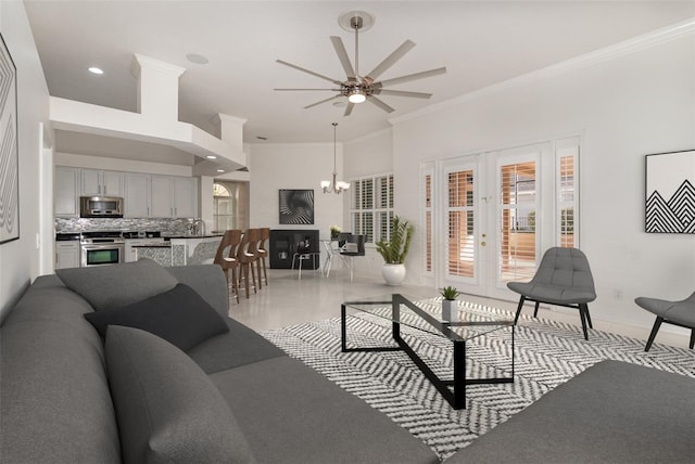 living room with ceiling fan with notable chandelier and crown molding