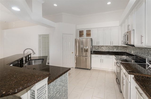 kitchen featuring appliances with stainless steel finishes, backsplash, dark stone counters, sink, and white cabinetry