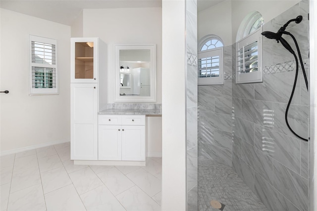 bathroom with tiled shower, vanity, and a healthy amount of sunlight