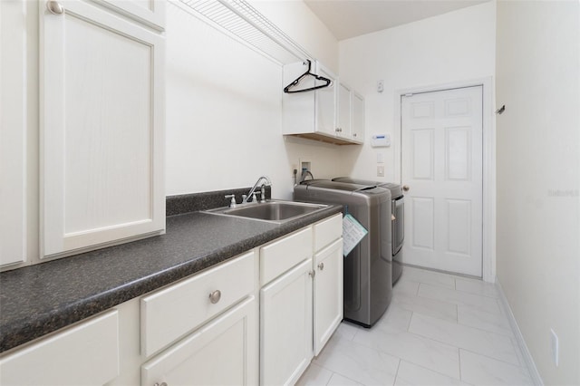 clothes washing area with washing machine and dryer, sink, light tile patterned floors, and cabinets