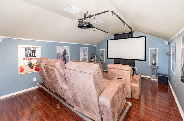 home theater room featuring a textured ceiling, dark hardwood / wood-style flooring, track lighting, and vaulted ceiling