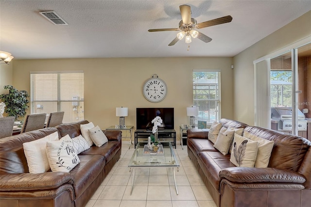 tiled living room with a textured ceiling and ceiling fan