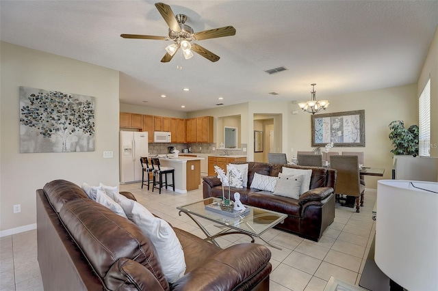 living room featuring ceiling fan with notable chandelier, sink, light tile patterned floors, and a textured ceiling