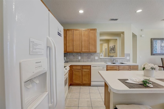 kitchen featuring kitchen peninsula, white appliances, a textured ceiling, sink, and light tile patterned floors