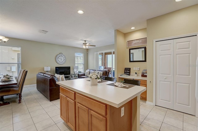 kitchen featuring ceiling fan, a center island, light tile patterned flooring, and a textured ceiling