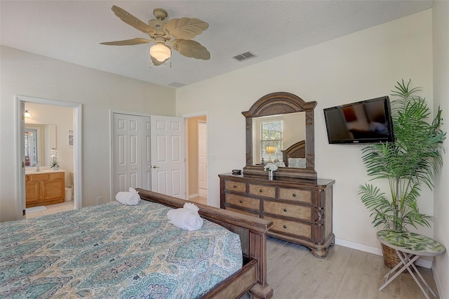 bedroom with light wood-type flooring, ensuite bath, ceiling fan, sink, and a closet