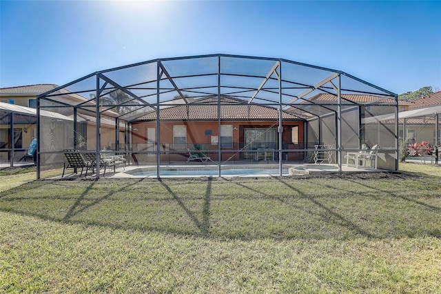 rear view of house featuring a lawn and glass enclosure