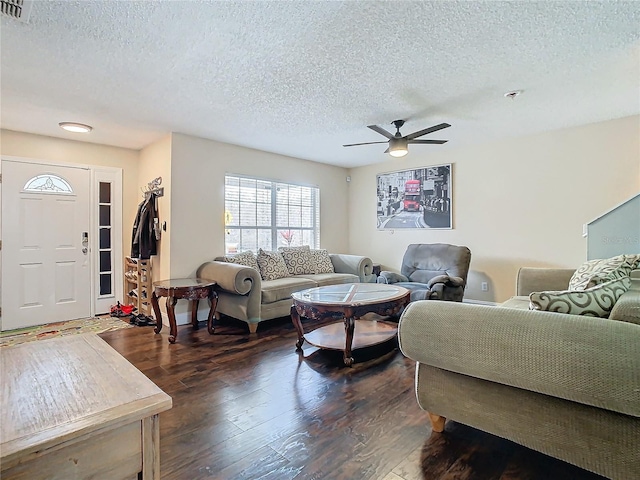 living room with a textured ceiling, dark wood-type flooring, and ceiling fan