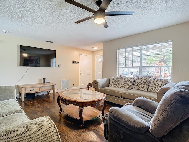 living room featuring ceiling fan, dark hardwood / wood-style floors, and a textured ceiling