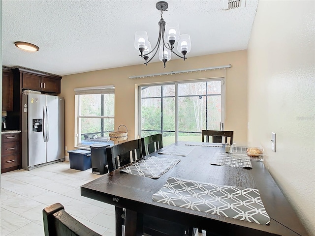 dining area with a textured ceiling and a notable chandelier