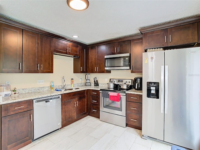 kitchen featuring light tile patterned flooring, sink, dark brown cabinetry, light stone countertops, and stainless steel appliances