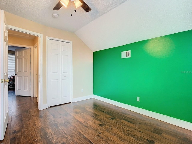 unfurnished bedroom with a textured ceiling, dark hardwood / wood-style floors, a closet, vaulted ceiling, and ceiling fan