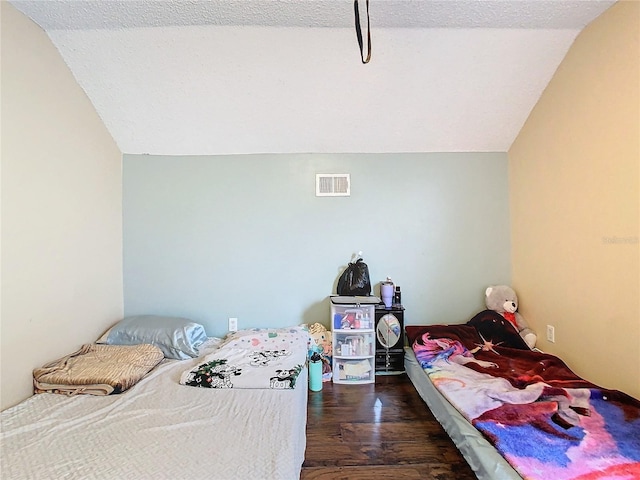 bedroom featuring a textured ceiling, dark hardwood / wood-style flooring, and lofted ceiling