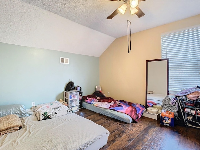 bedroom with ceiling fan, a textured ceiling, dark hardwood / wood-style floors, and vaulted ceiling