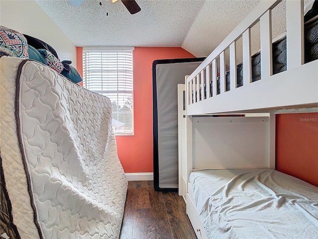 bedroom featuring ceiling fan, vaulted ceiling, dark hardwood / wood-style flooring, and a textured ceiling