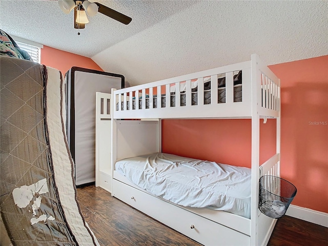 bedroom with ceiling fan, a textured ceiling, dark hardwood / wood-style flooring, and lofted ceiling