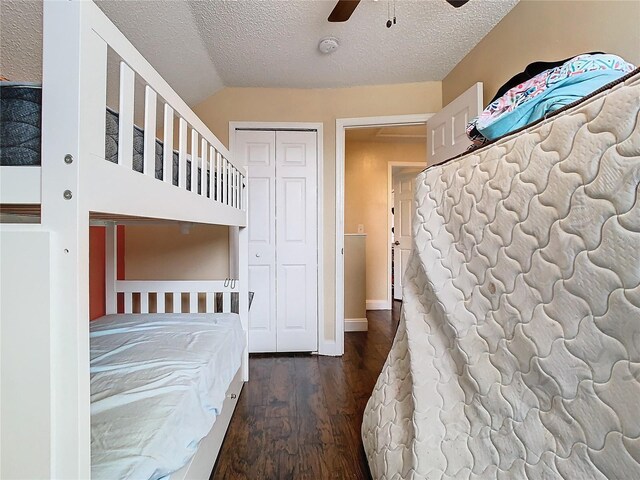 unfurnished bedroom with ceiling fan, a textured ceiling, dark hardwood / wood-style floors, and a closet