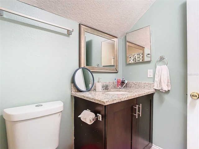 bathroom with a textured ceiling, toilet, lofted ceiling, and vanity